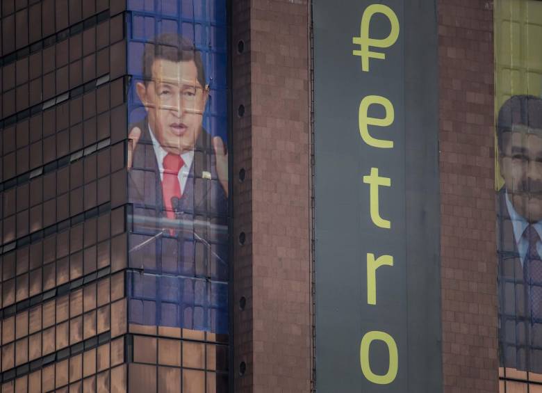Carteles del fallecido exmandatario Hugo Chávez, el actual presidente Nicolás Maduro y el logo de la moneda digital de Venezuela, petro, en un edificio de Caracas. FOTO: EFE