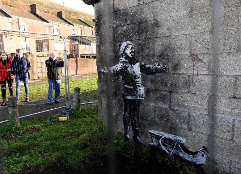 Unas personas miran la nueva creación de Banksy que apareció el 22 de diciembre de 2018 en Port Talbot, Reino Unido. Foto: REUTERS
