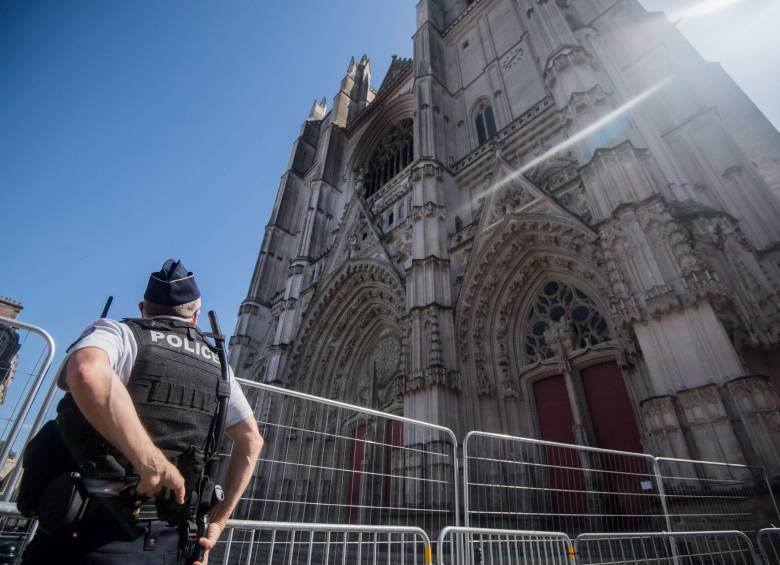 Un oficial de policía se encuentra frente a la fachada parcialmente quemada de la catedral de Saint-Pierre-et-Saint-Paul en Nantes. FOTO AFP