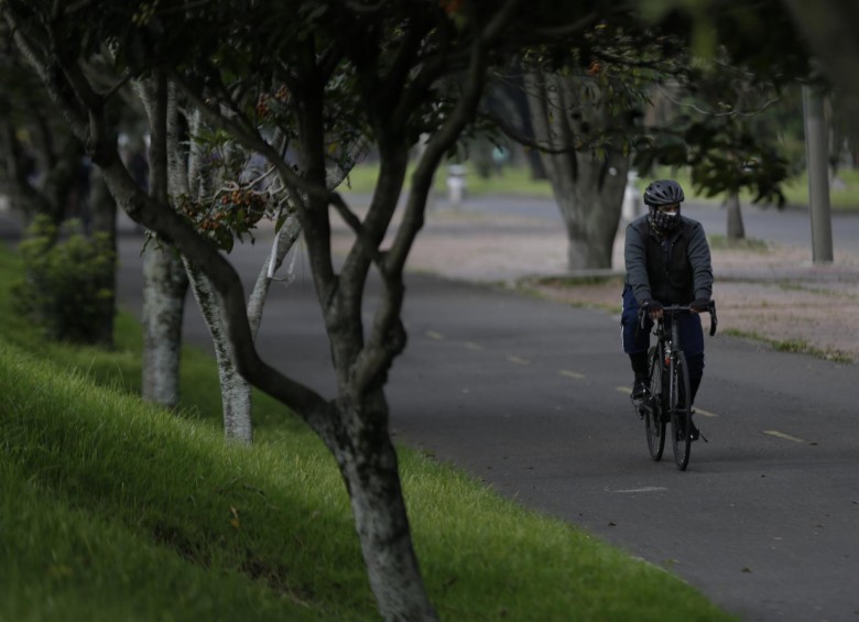 Un hombre monta en su bicicleta con medidas de protección, como el tapabocas. FOTO COLPRENSA