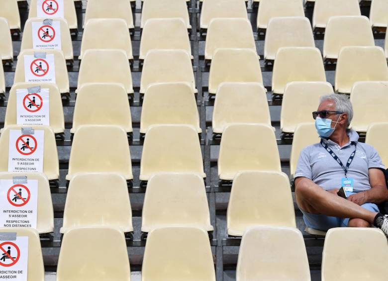 Un espectador se sienta cerca de letreros pidiendo distancia como precaución sanitaria para frenar la propagación de la enfermedad Covid-19. FOTO AFP