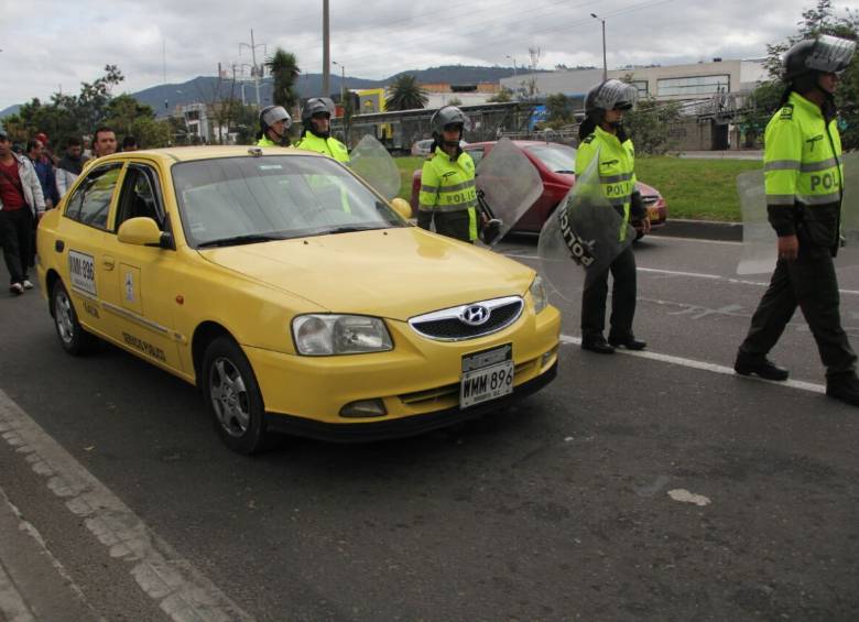 Uniformados de la Policía Nacional custodian el cese de actividades de los taxistas. FOTO COLPRENSA