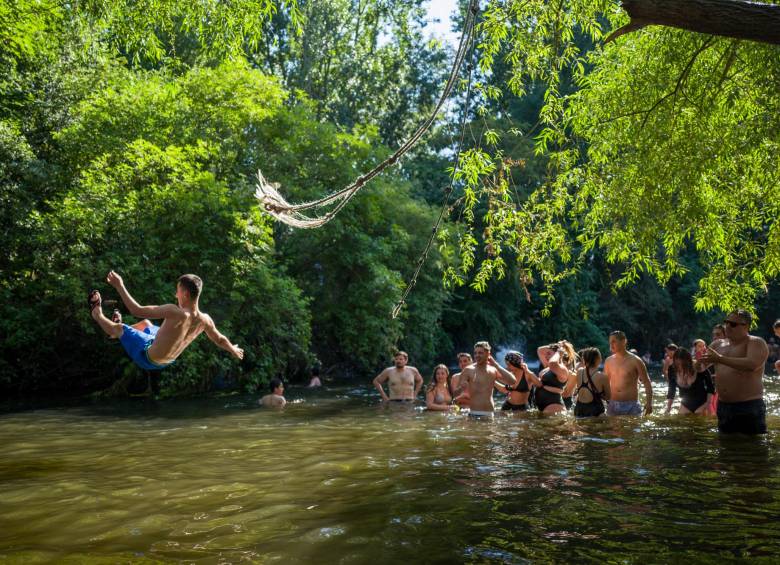 Personas se refrescan en el agua y toman el sol en la orilla del río en Hackney Marshes, en el este de Londres, el pasado 24 de junio, el día más caluroso del año. FOTO AFP