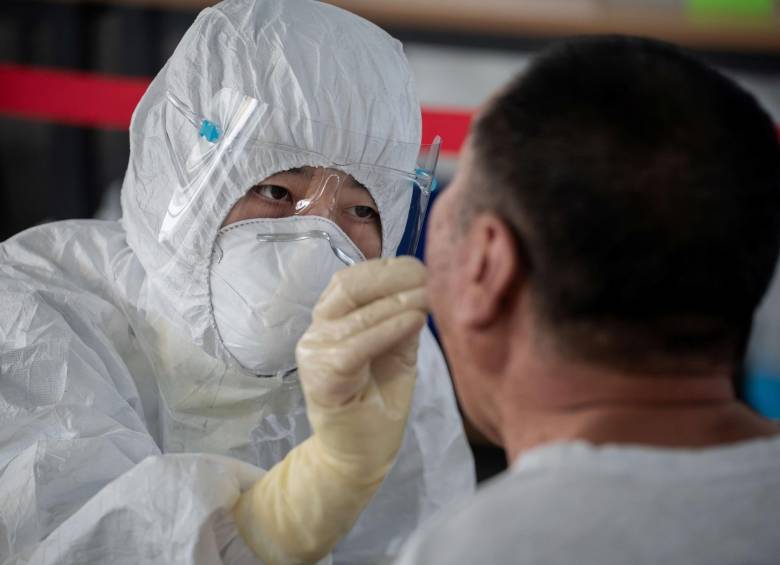 Un trabajador de la salud realiza una prueba de hisopo a un hombre en Pekín. FOTO AFP