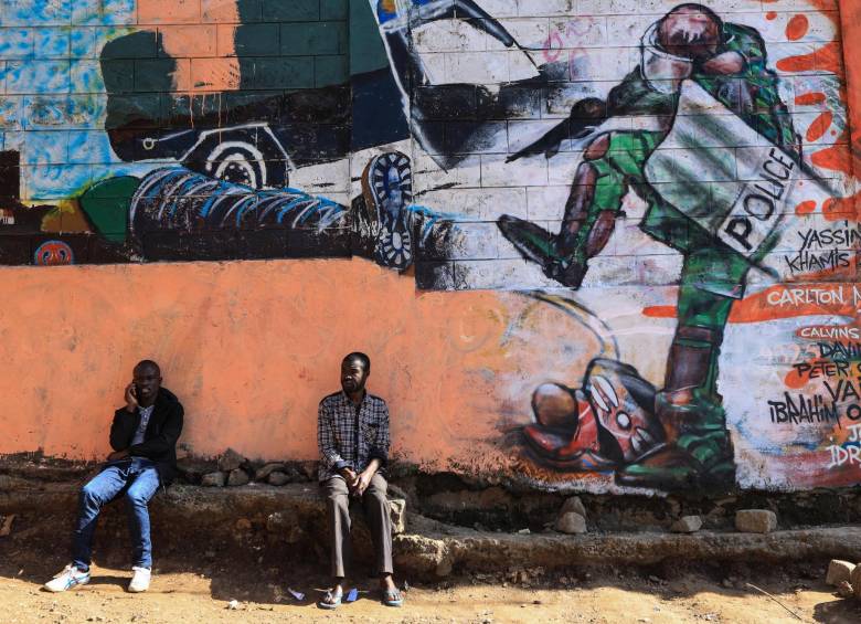 Dos hombres descansan junto a un mural que protesta contra la brutalidad policial. FOTO EFE