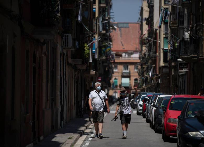 Dos personas con máscaras faciales caminan por el barrio de la Barceloneta en Barcelona. FOTO AFP