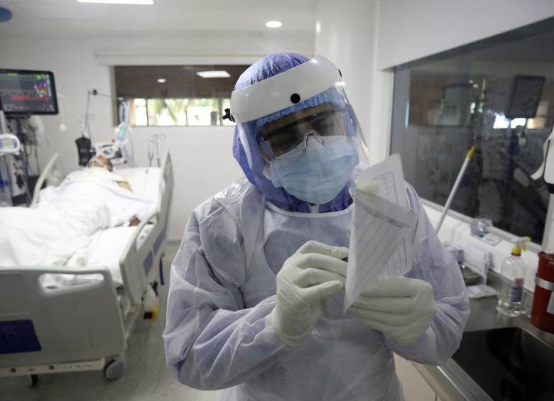 El terapeuta respiratorio escribe una nota después de tratar a un paciente infectado con Covid-19 en la Unidad de Cuidados Intensivos (UCI) de la Clínica CES en Medellín. FOTO AFP