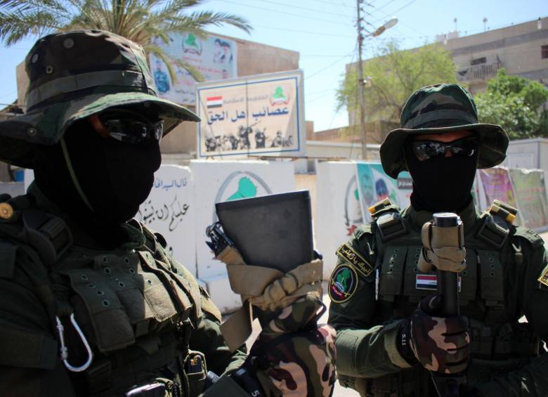 Combatientes iraquíes de la milicia chií Asaib Ahl al-Haq (La Liga de los Justos) montan guardia fuera de su sede en la sureña ciudad de mayoría chií iraquí de Basora, Las milicias chiítas se reunieron en Ramadi en un intento por recuperarla de yihadistas que invadieron la ciudad tras un bombardeo de tres días. FOTO AFP