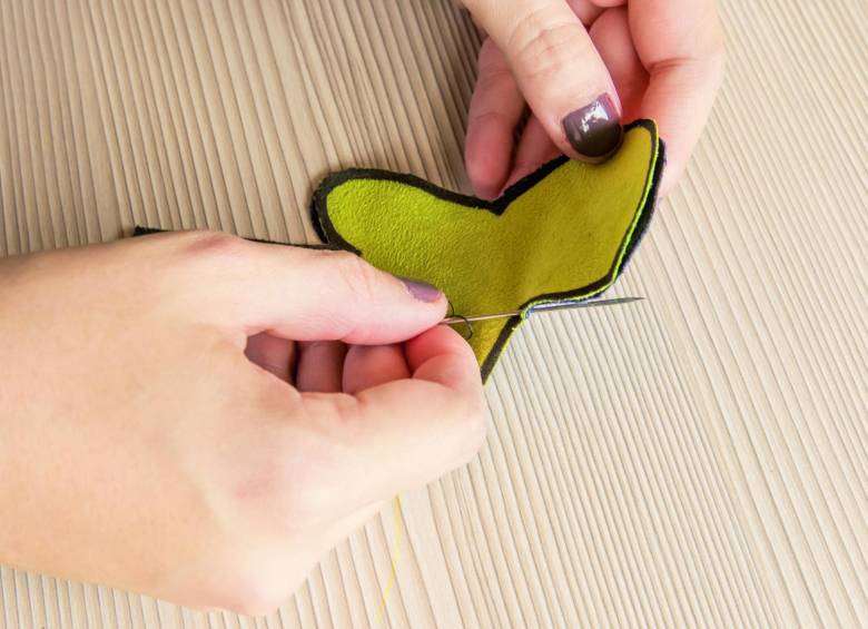 Junte las dos siluetas y, con aguja e hilo, comience a coser por todo el borde. 