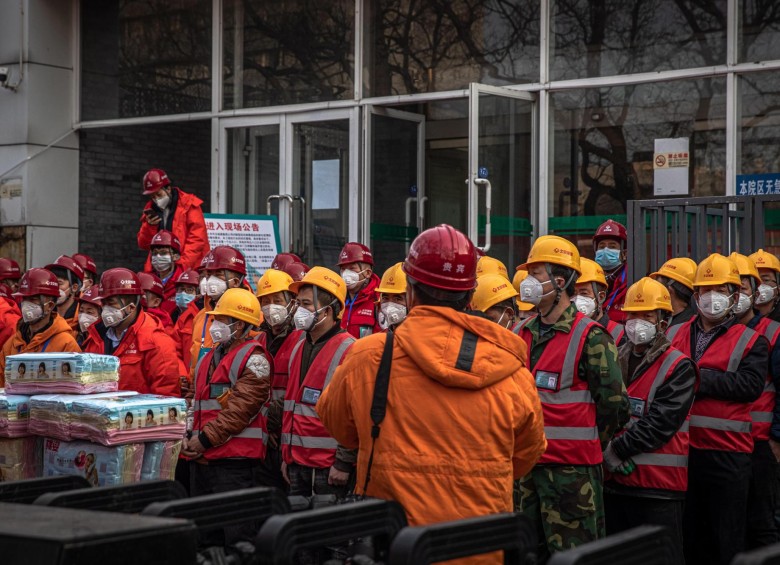 Trabajadores de la construcción con máscaras faciales protectoras se paran en una calle de Beijing, China. Foto EFE