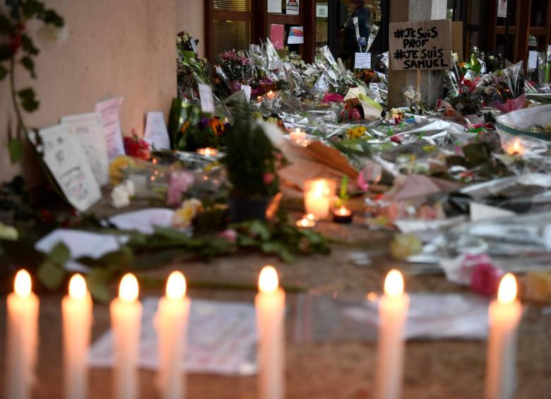 Flores, velas y un cartel que dice ‘Soy un maestro, soy Samuel’ en la entrada de una escuela secundaria en Conflans-Sainte-Honorine, 30 km al noroeste de París, después de que un maestro fuera decapitado por un atacante que ha sido asesinado a tiros por policías. Foto: AFP