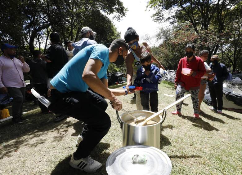 Ciudadanos venezolanos reciben comida en un campamento creado hace unos días, en el separador de la Autopista Norte, en Bogotá. FOTO EFE