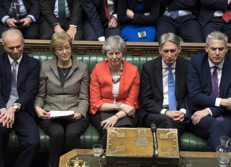 Theresa May (centro) junto a sus aliados durante la votación del acuerdo del Brexit este martes. FOTO: AFP