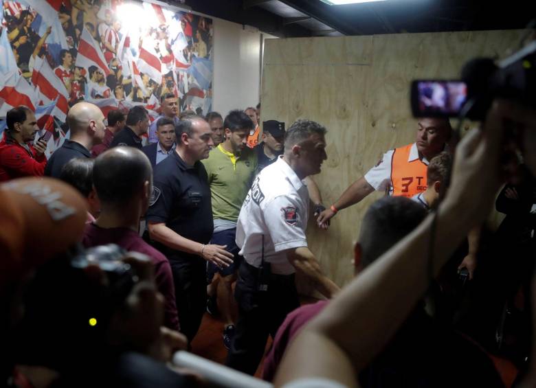 Pablo Pérez, capitán de Boca, camina junto a los paramédicos en el estadio Monumental. FOTO EFE