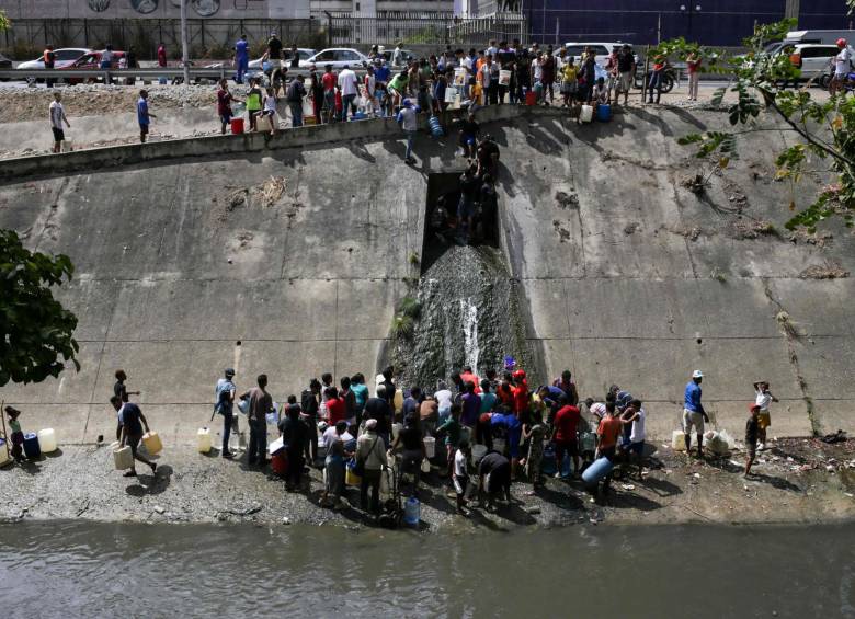 En el Canal del río Guaire en Caracas una multitud de personas llena baldes con agua para sus quehaceres diarios. FOTO AFP
