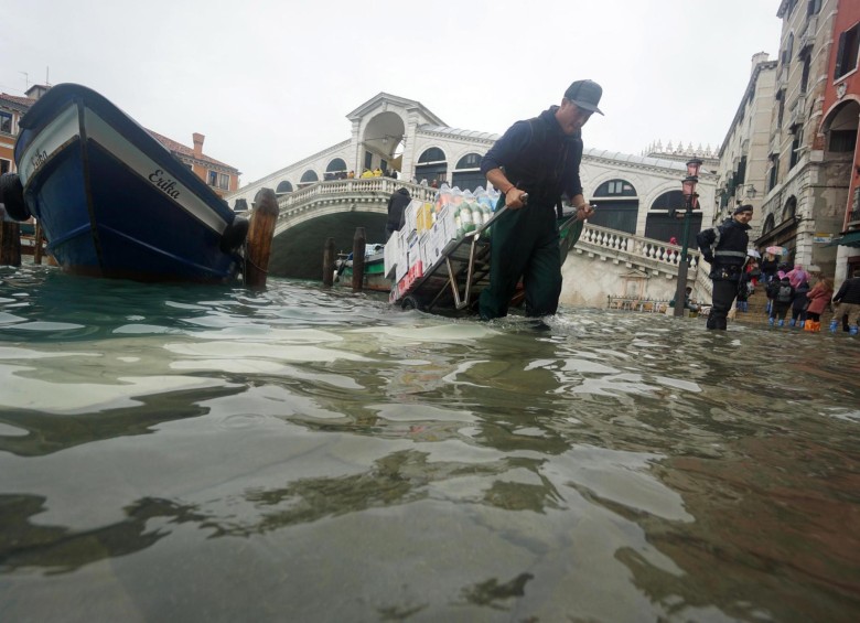 Un repartidor lleva su carrito a través de las inundaciones en Venecia. FOTO EFE
