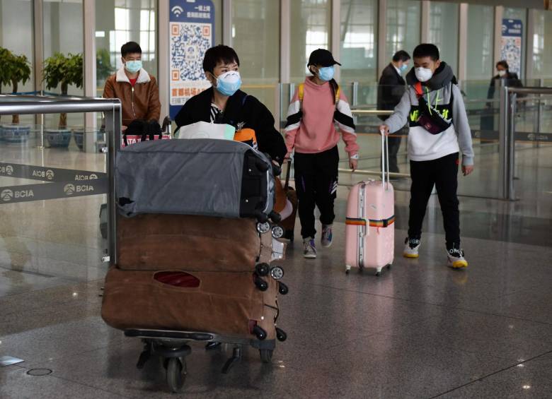 Los pasajeros usan mascarillas como medida preventiva contra el coronavirus COVID-19 cuando llegan de un vuelo internacional en el Aeropuerto Capital de Beijing. FOTO AFP