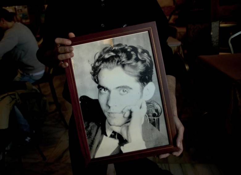 Un joven sostiene un retrato del poeta español Federico Garcia Lorca cerca al parque donde se cree está enterrado su cuerpo. FOTO AFP.