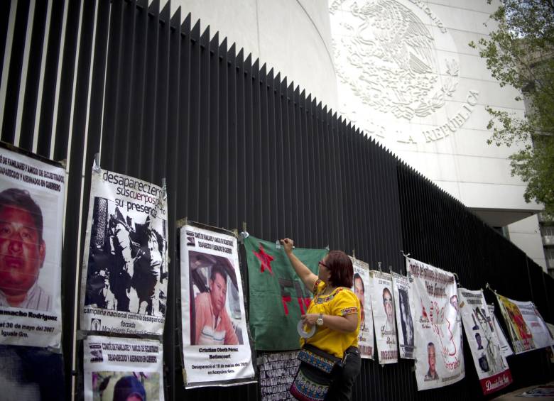 Un activista cuelga fotos de personas desaparecidas en el edificio del Senado de México al final de una marcha para protestar contra la desaparición forzada en la Ciudad de México. FOTO AFP