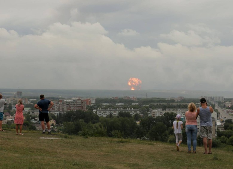 Personas observan cómo el fuego y el humo se elevan desde el lugar de una explosión en un depósito de municiones en Rusia el pasado 5 de agosto. FOTO REUTERS