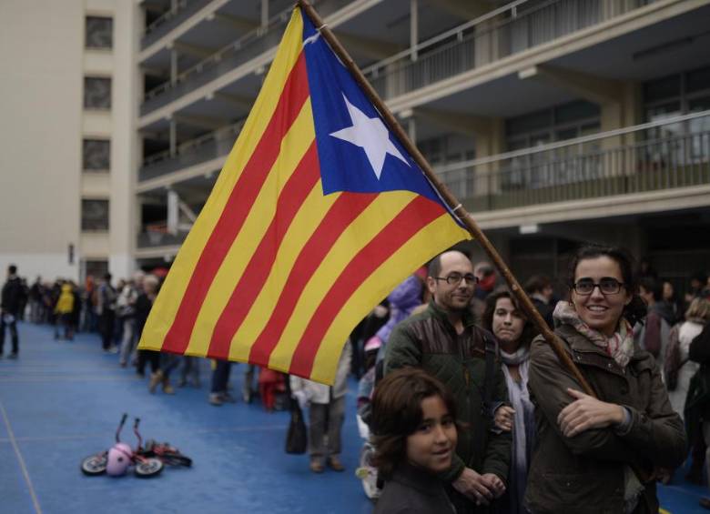 Una atmósfera festiva reinaba ayer, mientras cientos de personas hacían fila frente a un colegio de Barcelona, algunas de ellos con material de campaña a favor de la independencia. FOTO ap
