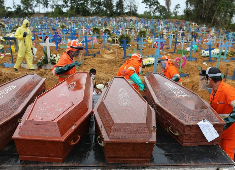 Especialistas han dicho que hay una alta subnotificación de casos debido a que el país no dispone de suficientes pruebas. La foto del pasado 6 de mayo capta el momento en que depositan ataúdes en una fosa común en el cementerio Nuestra Señora, Manaos, estado amazónico de Brasil. FOTO AFP
