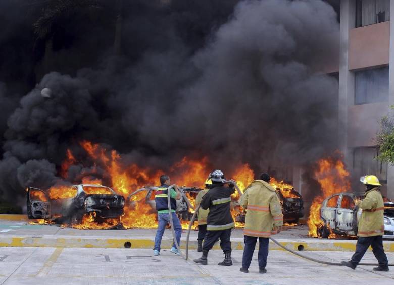 Momento en el que los bomberos intentan controlar el incendio de media docena de automóviles parqueados en el Congreso de Guerrero. FOTO AP