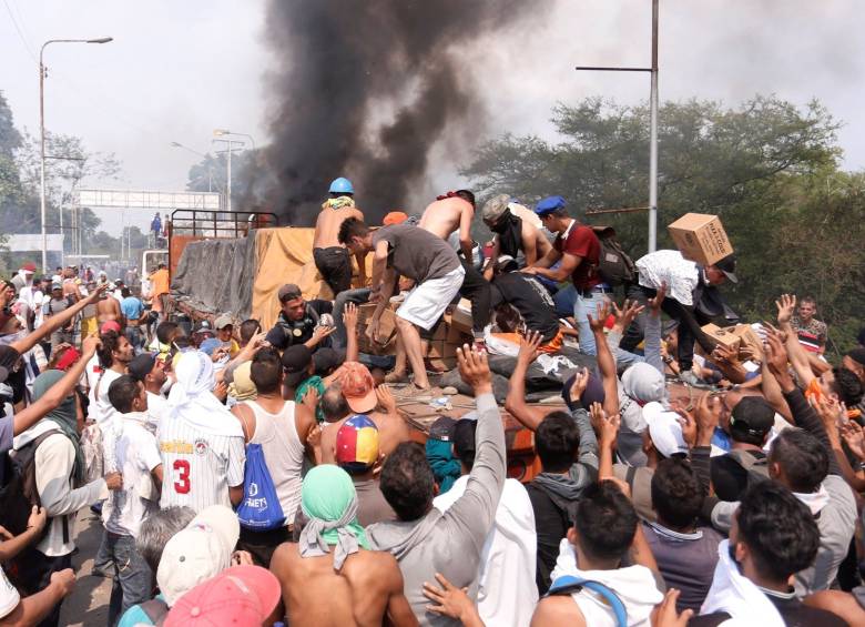 Personas intentan sacar parte de la ayuda humanitaria que se encuentra un camión que fue quemado, este sábado, en Ureña (Venezuela). FOTO: EFE