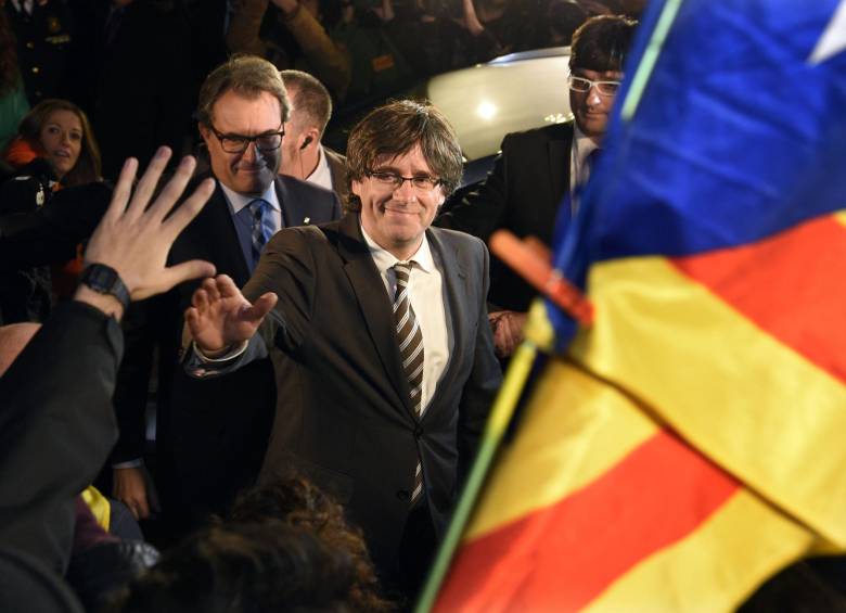 El nuevo presidente de Cataluña, Carles Puigdemont, saluda a sus seguidores después de la elección. Lo sigue Artur Más quien hasta el pasado domingo fue presidente de esa región española que continúa con intenciones de independizarse. FOTO Afp