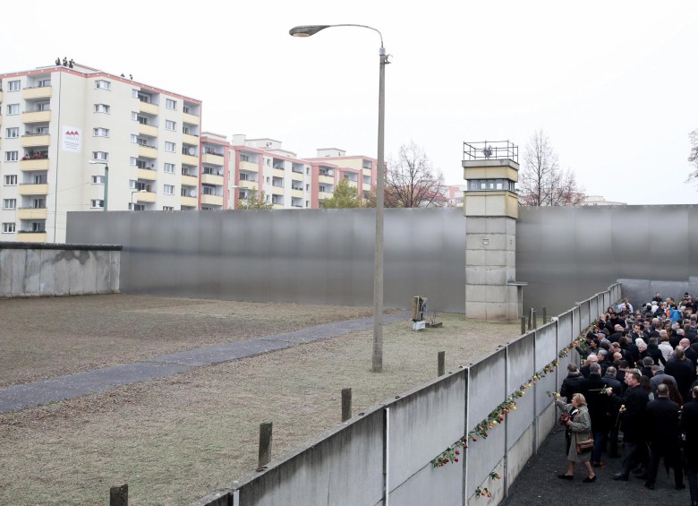 Ciudadanos ponen rosas sobre la representación de la “franja de la muerte” que existe en el Memorial del Muro al lado de la calle Bernauer en Berlín. FOTO EFE