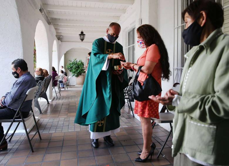 En Los Angeles, California, el reverendo Arturo Corral recorre los pasillos de su templo para llegar con la comunión, de manera individual, a los feligreses. Los Angeles-AFP