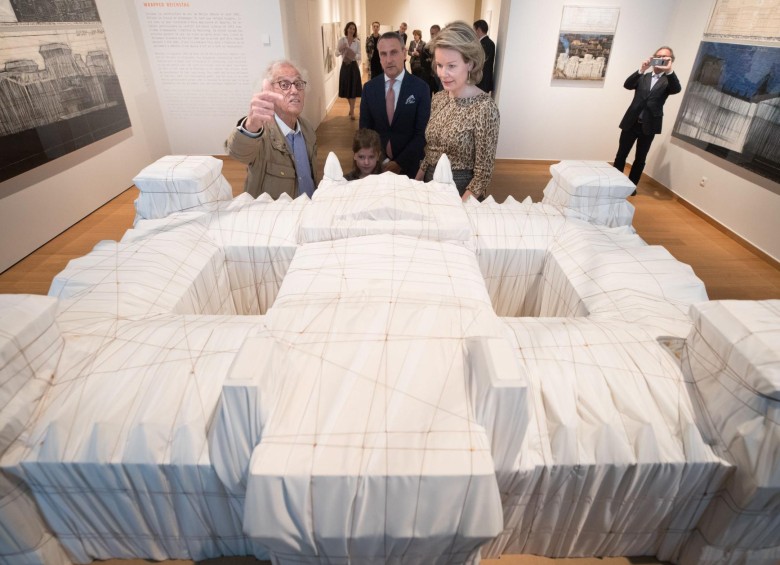 Christo le explica a la reina Matilde de Bélgica un modelo de su trabajo Wrapped Reichstag de 1995 en una visita a la exposición Christo and Jeanne-Claude: Urban Projects en Bruselas. Foto: BENOIT DOPPAGNE / AFP