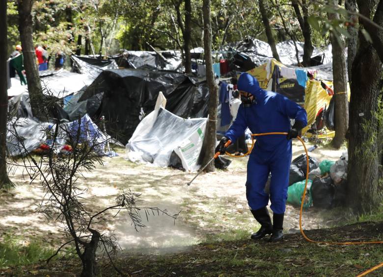 Un trabajador de la Alcaldía de Bogotá desinfecta el lugar donde se concentran más de 500 venezolanos. FOTO EFE