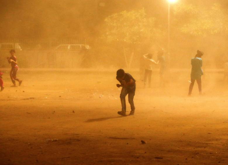 Niños se cubren durante la tormenta de arena, en Nueva Delhi. Foto Reuters.