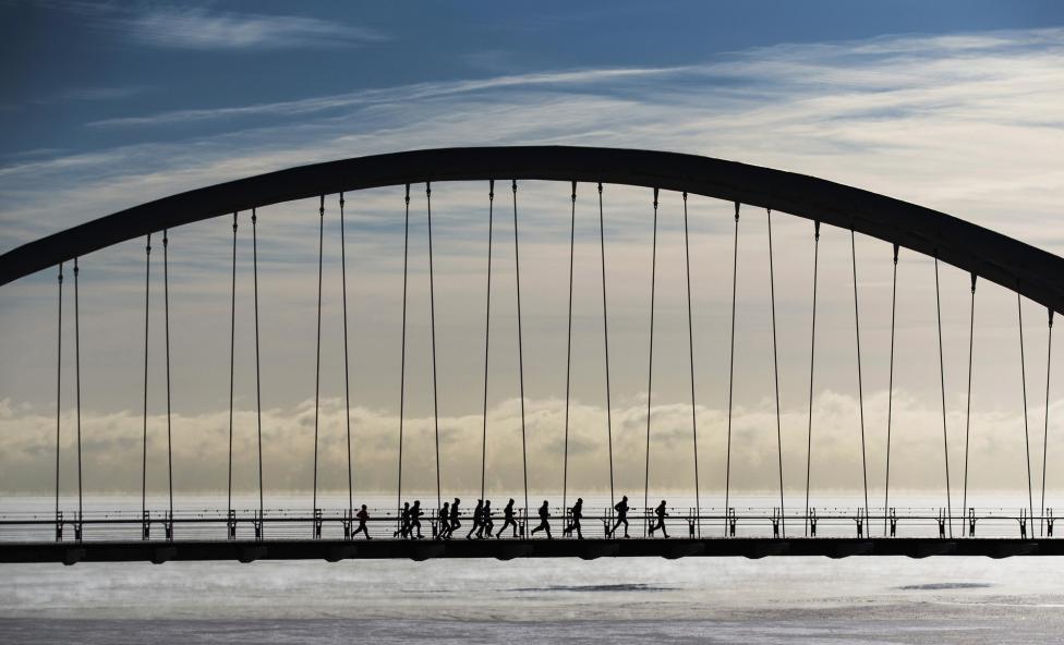 Un grupo de corredores atraviesan el puente del arco de la Bahía de Humber pese a las temperaturas de frío extremo en Toronto. FOTO REUTERS