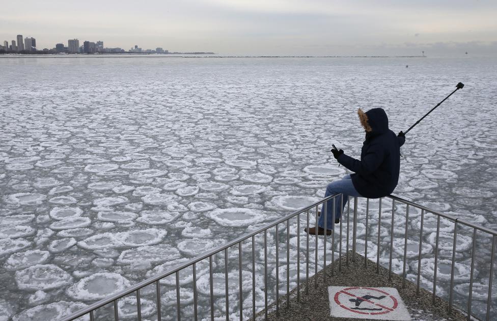 Carlos Martínez en una baranda busca tomar una foto con vista al parcialmente congelado lago Michigan en Chicago, Illinois. FOTO: Jim Young / REUTERS 