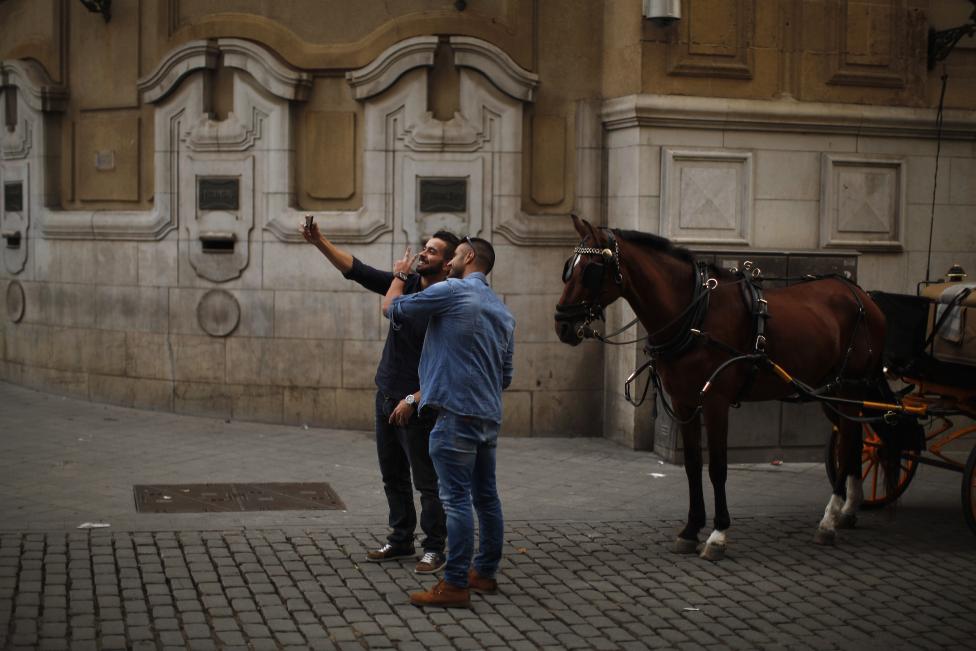 Dos hombres se toman un selfie con un caballo en el centro de la capital andaluza de Sevilla. FOTO: Jon Nazca / REUTERS 