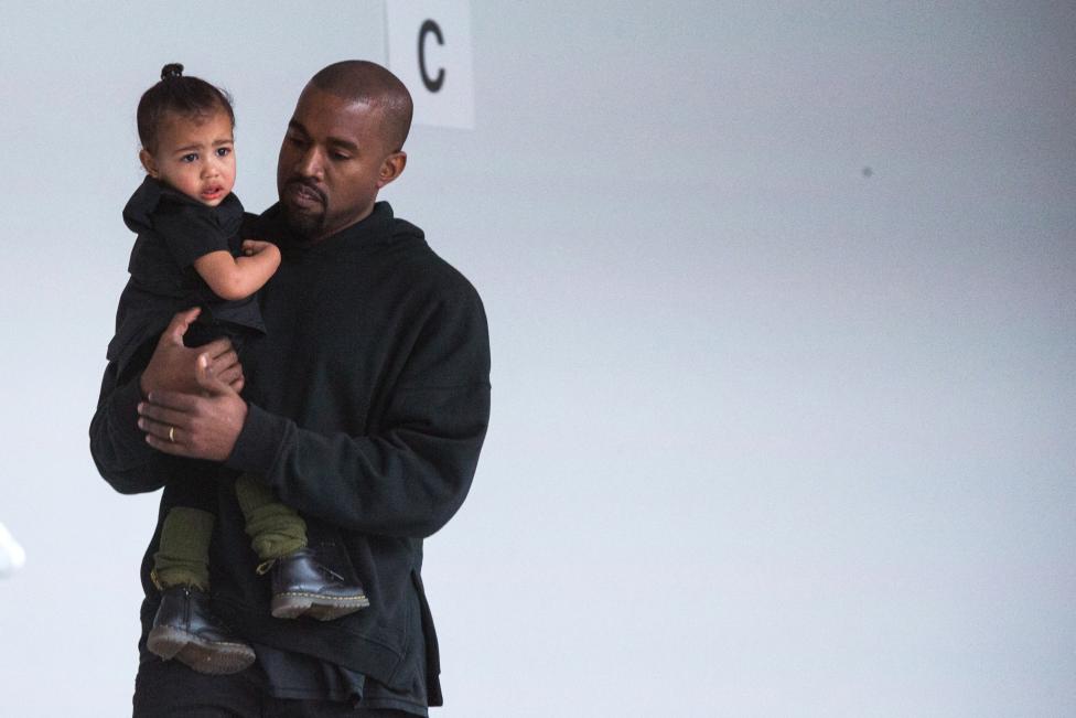 Kanye West carga a su hija, mientras se prepara para el desfile. FOTO REUTERS