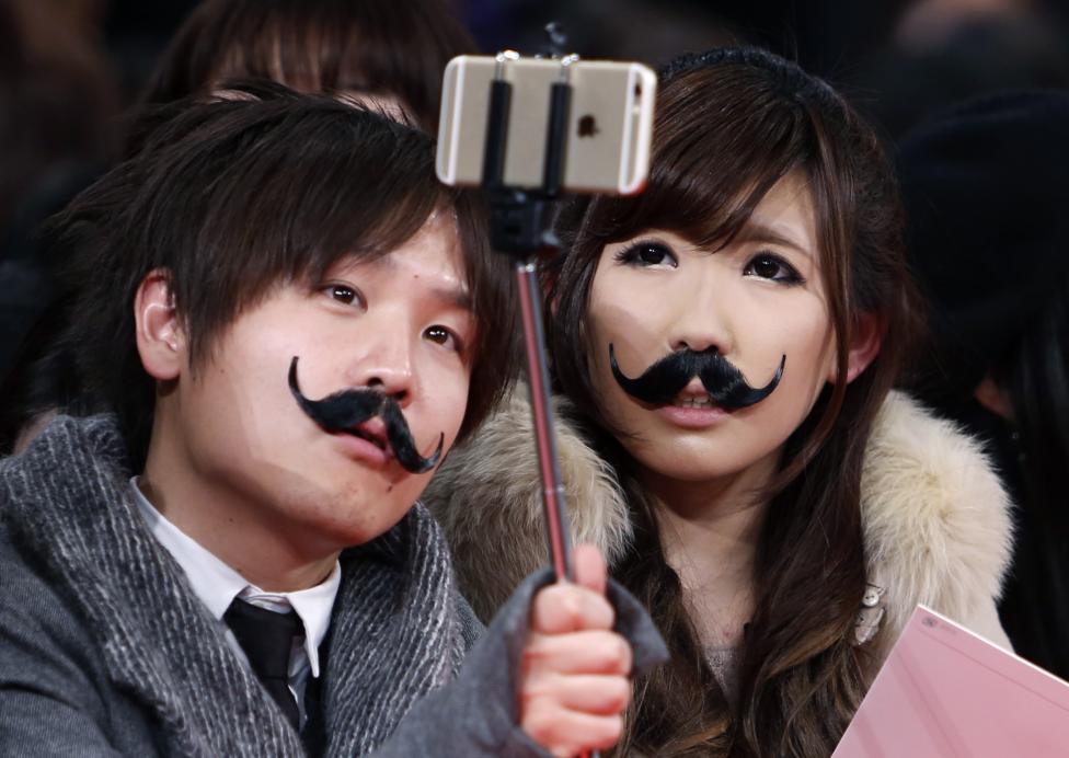 Una pareja que usa bigotes falsos se toman una foto mientras esperan el estreno de “Mortdecai “ en Tokio. FOTO: Yuya Shino / REUTERS