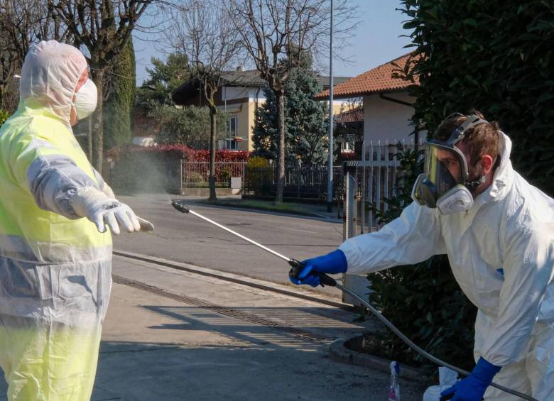Miembros de Protección Civil, en Italia, desinfectan sus implementos de protección personal después de una jornada en medio de la pandemia. FOTO EFE