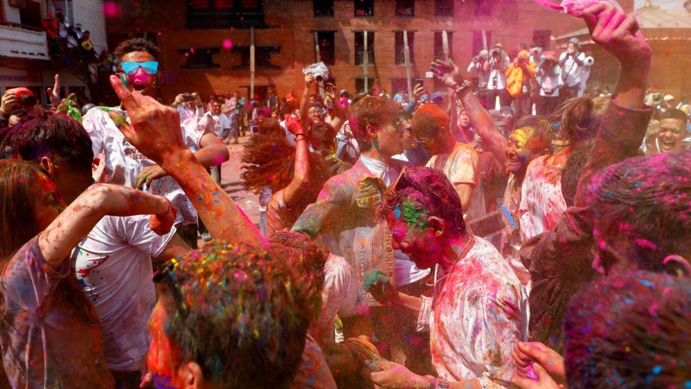 Los jóvenes sonríe embadurnados de colores mientras una multitud celebra, este miércoles, el festival Holi . Foto: EFE / Divyakant Solanki 