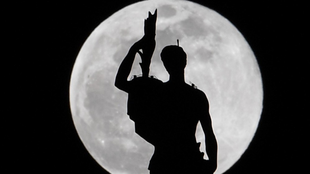 Una estatua en la cima de la Catedral del Duomo de Milán se representa mientras la Luna de Súper Nieves se levanta. Foto: AFP