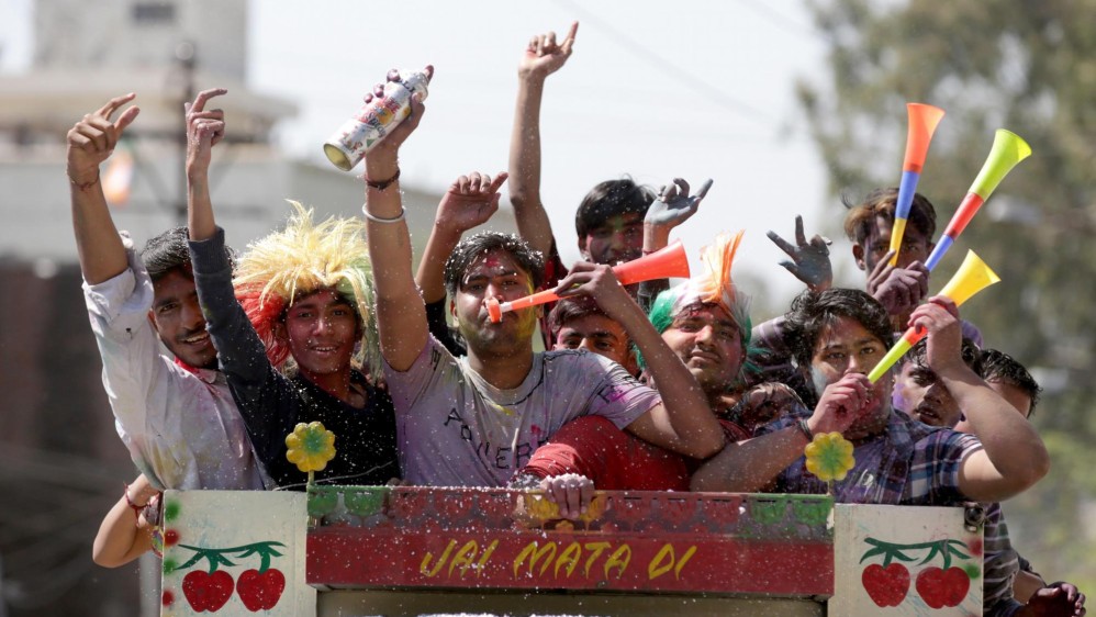 Los jóvenes sonríe embadurnados de colores mientras una multitud celebra, este miércoles, el festival Holi. Foto: EFE/ Divyakant Solanki