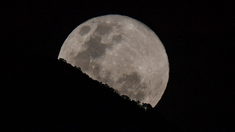 La súper luna es fotografiada mientras se eleva detrás del cerro El Ávila en el cielo de Caracas, Venezuela. Foto: AFP